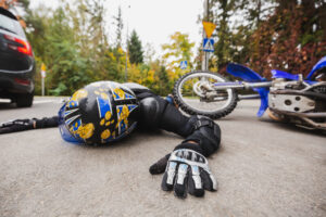 Man in leather suit and helmet lying on the street after the accident