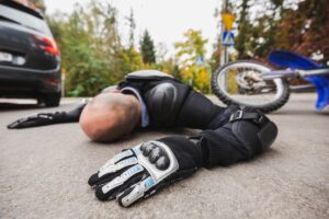 Motorcycle driver without the helmet laying on the road after accident