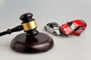 Judge's gavel beside car accident models on a gray background, symbolizing legal proceedings and car accident cases.