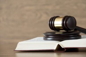 A wooden gavel resting on a stack of law books atop a wooden table. 