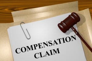 A rendered illustration of the title "Compensation Claim" prominently displayed at the top of a legal document. The document appears official, with lines of text suggesting legal language related to compensation. The background is neutral, focusing on the formal, structured appearance of the legal paperwork, emphasizing the process of filing a compensation claim.