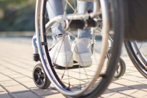 A close-up of a person’s feet resting on a wheelchair, representing mobility issues or injuries after an accident.